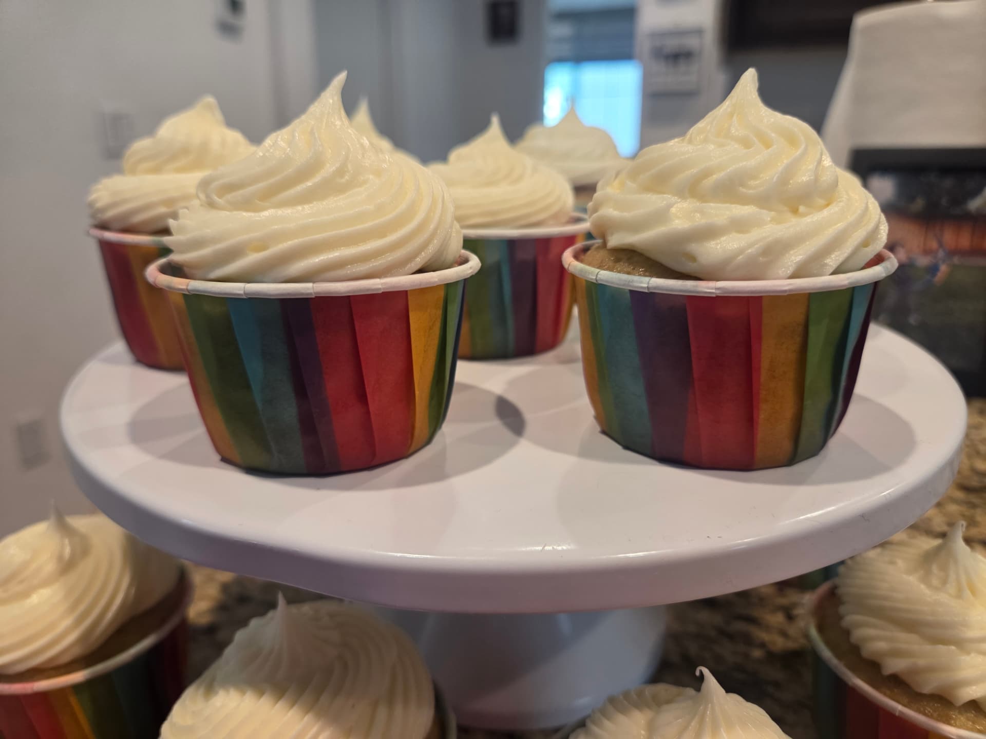Cupcakes in rainbow liners on a white cake stand