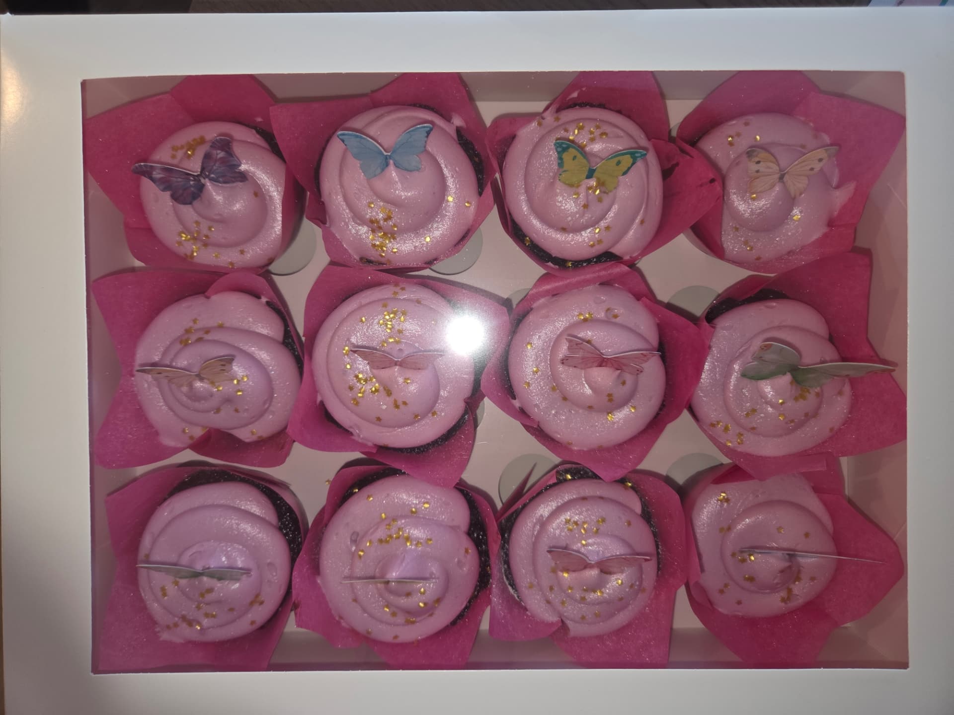 Boxed dozen of pink butterfly cupcakes with gold sprinkles