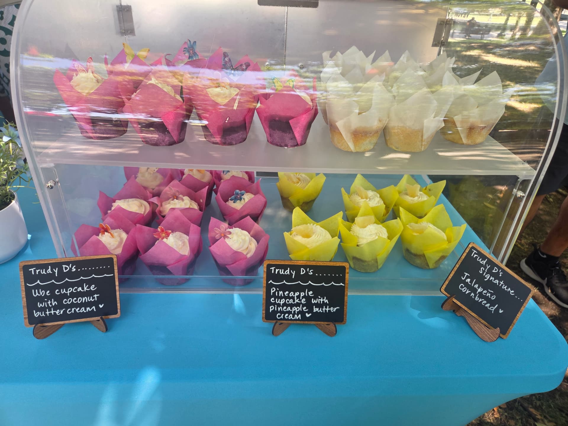 Market display case of ube, pineapple and jalapeño cornbread with Trudy D's chalkboard signs