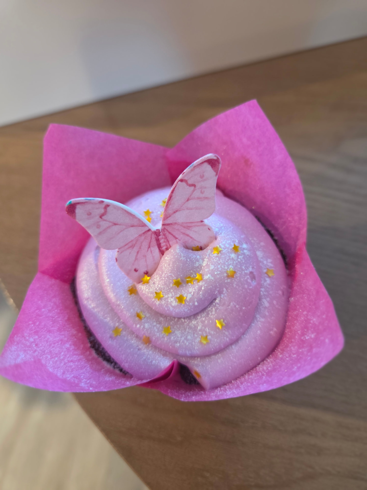 Pink butterfly cupcake with gold star sprinkles in a pink tulip liner