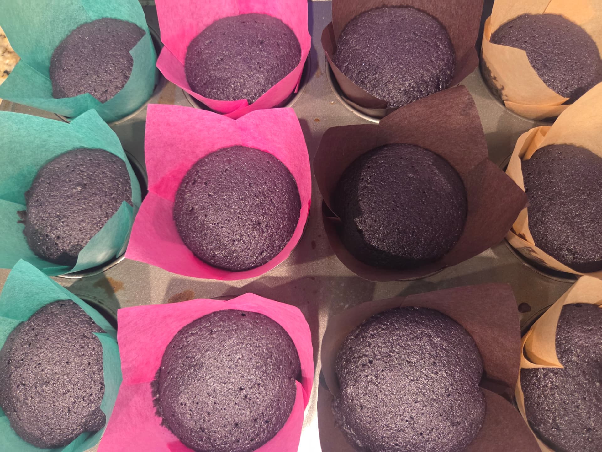 Freshly baked ube cupcakes in colorful tulip liners